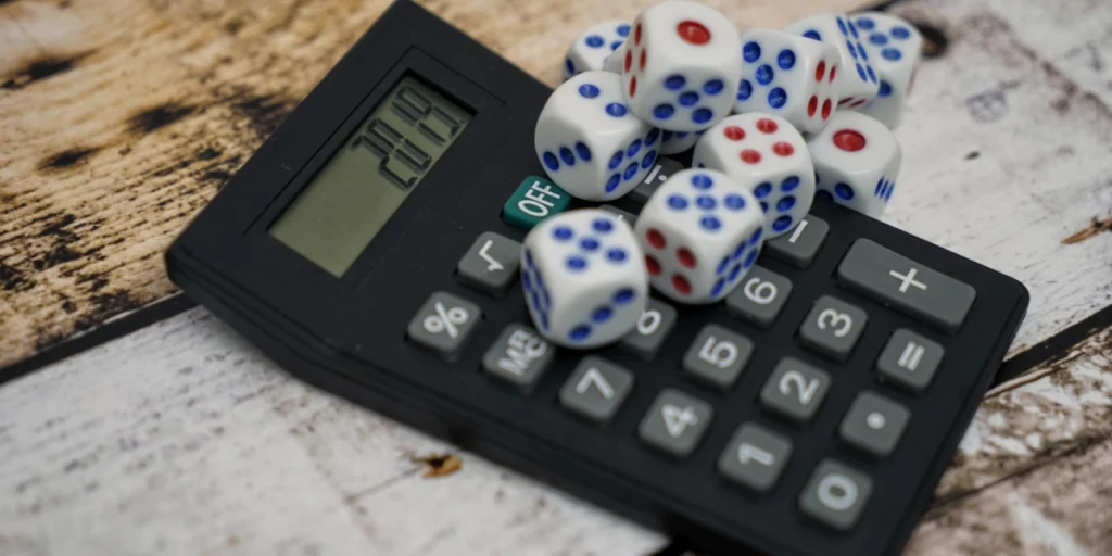 Calculadora sobre una superficie de madera con varios dados encima, que simbolizan el cálculo de probabilidades, odds e implied odds en juegos de azar.